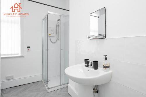 Spacious 5-Bedroom Oasis with Games Room-Liverpool في ليفربول: حمام أبيض مع حوض ودش