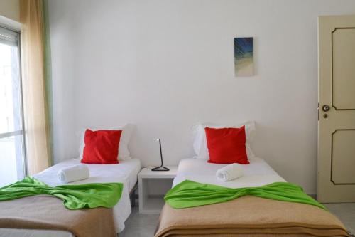2 camas en una habitación con almohadas rojas y verdes en Alvor House Lagoon, en Alvor