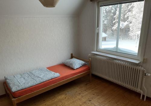 a small bed in a room with a window at House in the middle of forests and lakes in Svartträsk