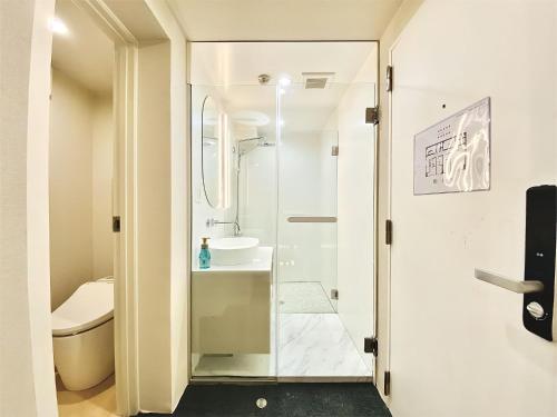 un baño con una puerta de cristal que conduce a un lavabo en 东京上野超级中心 设计师房间Ycoe 上野公园3分钟 车站1分钟 超级繁华 免费wifi 戴森吹风, en Tokio