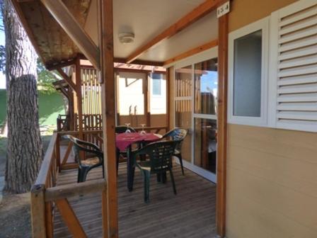 a house with a table and chairs on a deck at Camping Barraquetes in Sueca