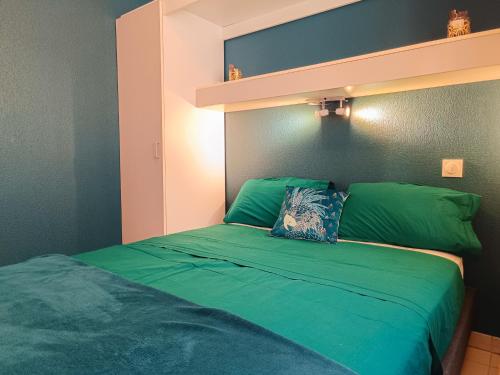 a bedroom with a green bed with a shelf at Magnifique vue mer et piscine - Les Clés de L Estérel in Théoule-sur-Mer
