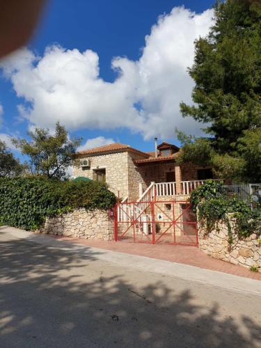 a house with a red gate and a stone wall at Stone Edge Homestead in Agios Leon