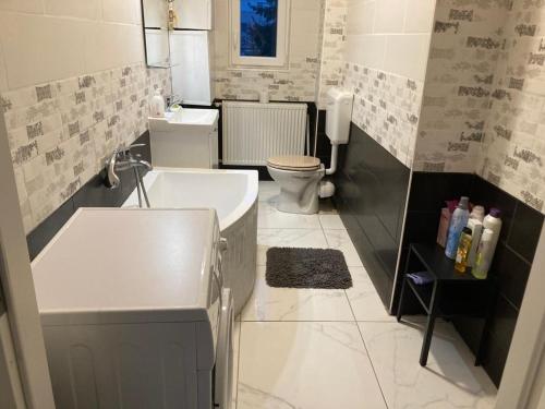 a bathroom with a tub and a toilet and a sink at City Center Superb inside 3 Bedroom+Living room Apartment in Szombathely