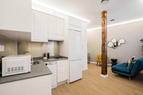 una cocina con armarios blancos y una silla azul en Plaza Mayor cozy Private apartment with AC, en Madrid