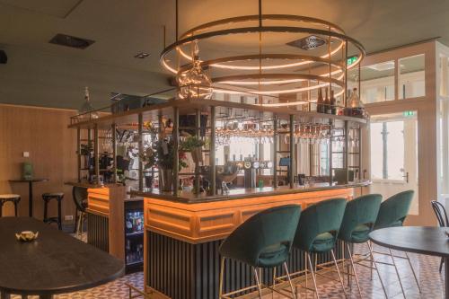 un bar avec des chaises vertes et un lustre dans l'établissement Wapen van Hengelo Residence Suites - digital key by email, à Hengelo