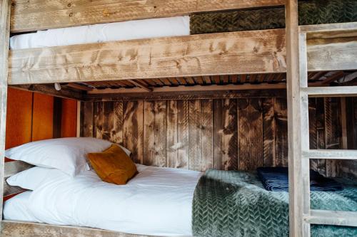 una camera con 2 letti a castello e lenzuola bianche di Fibden Farm Glamping - Luxury Safari Lodge a Droitwich