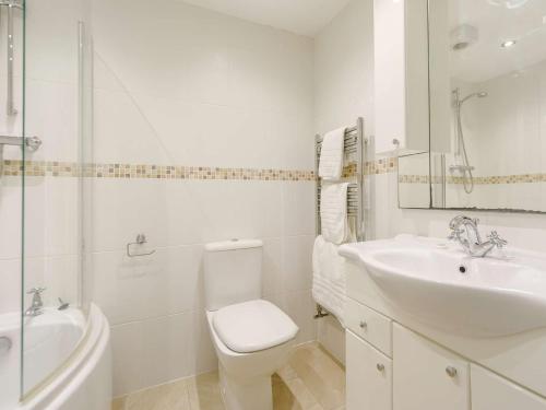 a white bathroom with a toilet and a sink at 3 Bed in Newquay 89941 in Mawgan Porth
