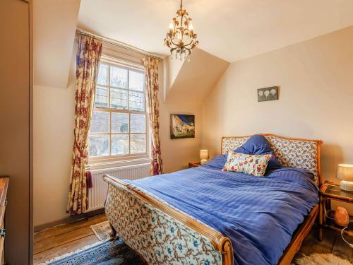 a bedroom with a bed with blue sheets and a window at 2 Bed in Ironbridge 89961 in Coalbrookdale