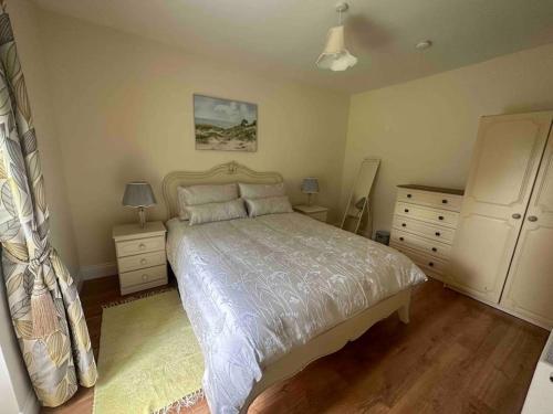 a bedroom with a bed and two night stands and a dresser at Wildflower Cottage in Clonmel