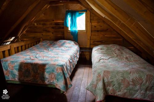 a attic room with two beds and a window at La Cabaña de Blanca in Jalpan de Serra