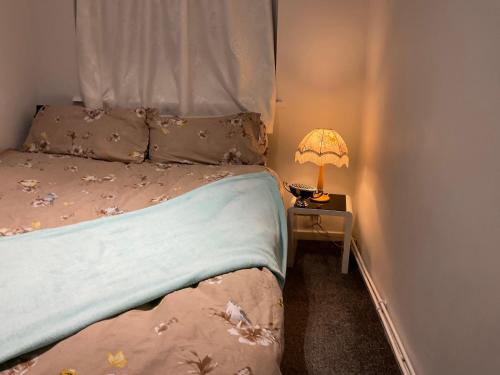 a bedroom with a bed and a lamp on a table at Feel at home in Abbey Wood