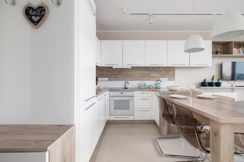 une cuisine avec des placards blancs et une table en bois dans l'établissement Studio Tysiąclecia next to Park Śląski Katowice by Renters, à Katowice