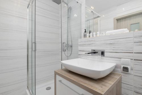 La salle de bains blanche est pourvue d'un lavabo et d'une douche. dans l'établissement Studio Tysiąclecia next to Park Śląski Katowice by Renters, à Katowice