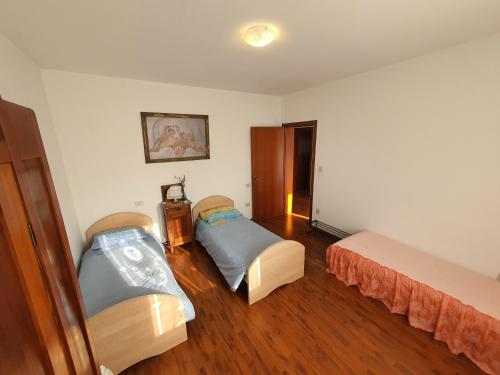 a room with two beds in a room with wooden floors at Casa Ortensia in Grions