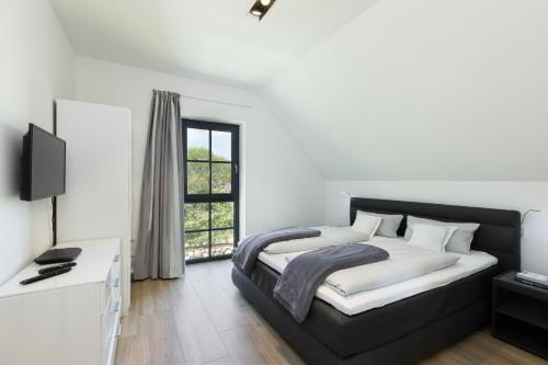 um quarto com uma cama, uma secretária e uma janela em Reetdachhaus Strandperle em Hohenkirchen