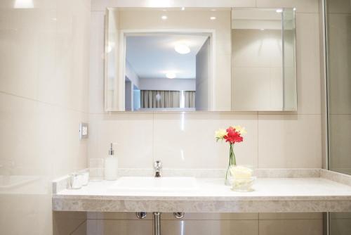 a bathroom with a sink with a vase of flowers at Byblos Palermo Soho in Buenos Aires