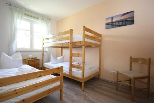 キュールングスボルンにあるStrandschloesschen-Haus-II-WE-18-9723のベッドルーム1室(二段ベッド2台、椅子付)