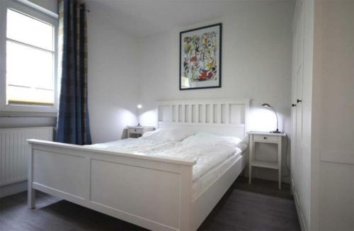 a white bedroom with a large white bed and a window at Strandschloesschen-Haus-II-WE-4-9699 in Kühlungsborn