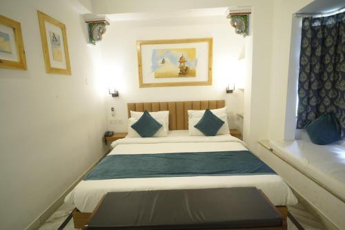 a bedroom with a bed with a blue blanket at Hotel Banjara Heritage in Udaipur