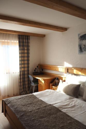 a bedroom with a bed and a desk and a window at Ferienwohnung Gompitzer in Heiligenblut