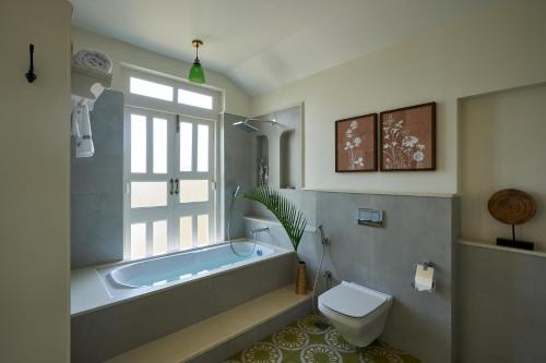 a bathroom with a tub and a toilet and a sink at LohonoStays Villa Aurelia E in Vagator