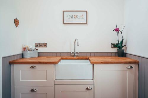 a kitchen with white cabinets and a sink at Beautiful cottage in idyllic countryside setting in Montgomery