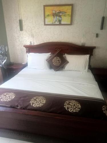 Schlafzimmer mit einem großen Bett mit einem Kopfteil aus Holz in der Unterkunft CRYSTAL SUITES in Akure