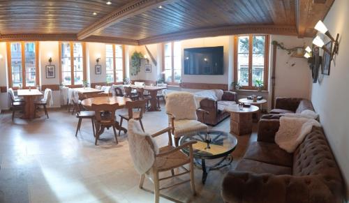 uma sala de estar com sofás, mesas e cadeiras em Hotel de Commune em Gstaad