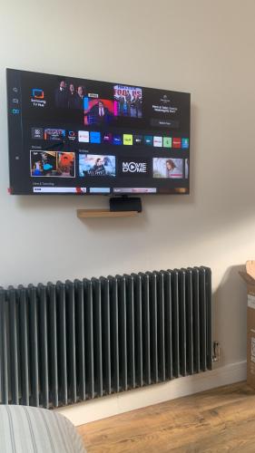 a flat screen tv hanging on a wall with a radiator at Swallows Nest in Gotham