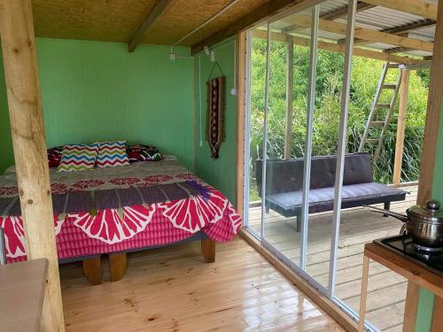1 dormitorio con 1 cama en una habitación con porche en Los carbon, en Ancud