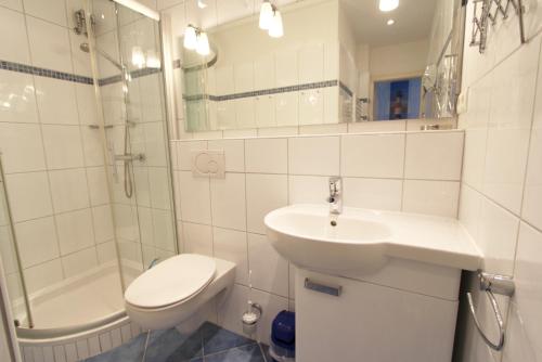 une salle de bain avec un lavabo, des toilettes et une douche dans l'établissement Atlantik - Strandstr 15, App 12, à Wenningstedt
