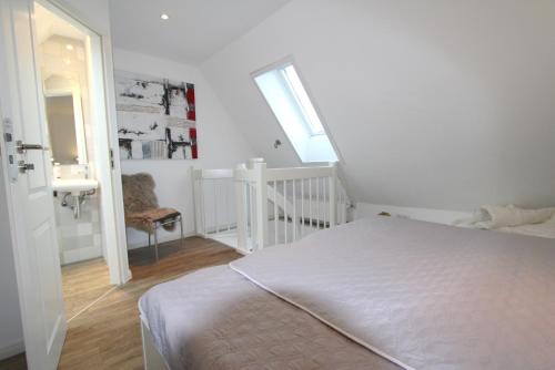 um quarto branco com uma cama e uma escada em Feldmarkstraße 5, App 10 em Wenningstedt