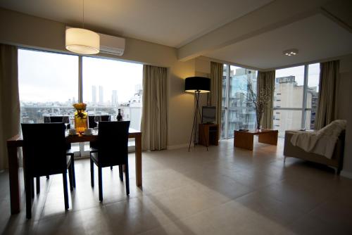 a living room with a table and chairs and a large window at Byblos Palermo Soho in Buenos Aires