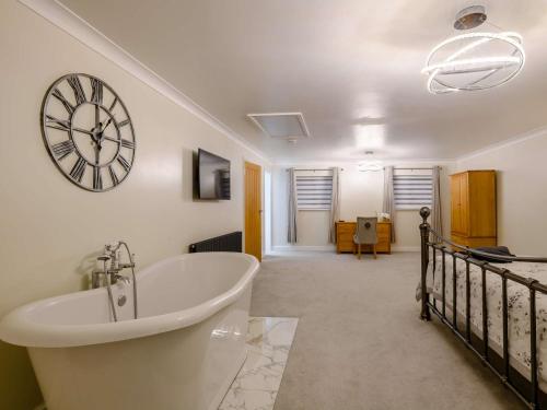 a bathroom with a tub and a clock on the wall at 4 Bed in Aylsham 90094 in Stratton Strawless