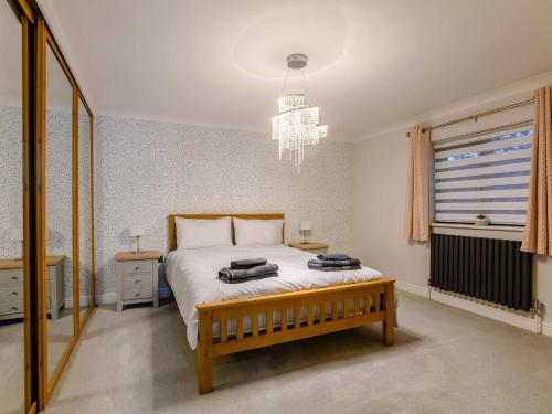 een slaapkamer met een bed en een kroonluchter bij 4 Bed in Aylsham 90094 in Stratton Strawless
