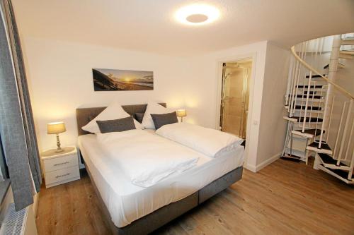 um quarto com uma cama com lençóis brancos e almofadas em Neptun - Dünenstr 2, App 4 em Wenningstedt