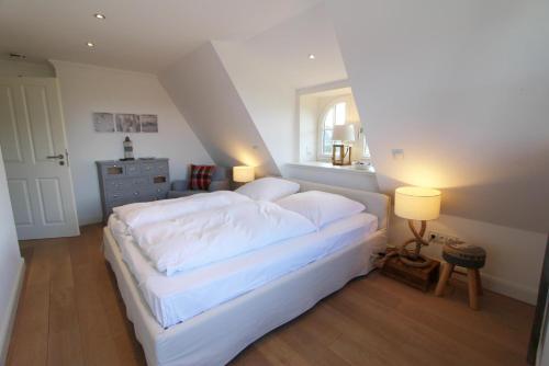 um quarto com uma cama com lençóis brancos e uma janela em Horsa Hüs - Westerlandstr 22 B em Wenningstedt