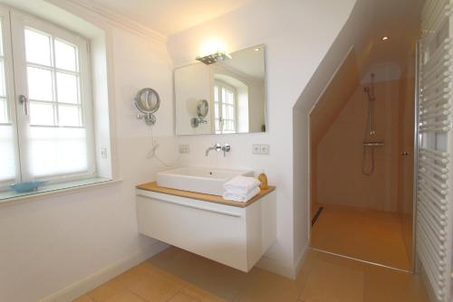 uma casa de banho branca com um lavatório e um espelho em Horsa Hüs - Westerlandstr 22 B em Wenningstedt