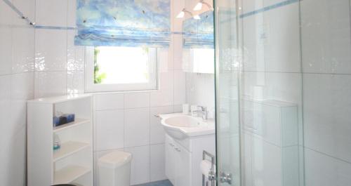 a white bathroom with a sink and a shower at Denghoog- Osetal 10, App 2 in Wenningstedt