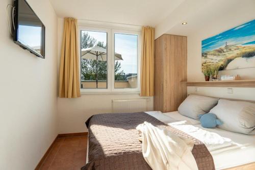 1 dormitorio con cama y ventana en Strandpark-Grossenbrode-Haus-Leuchtturm-Wohnung-8, en Großenbrode