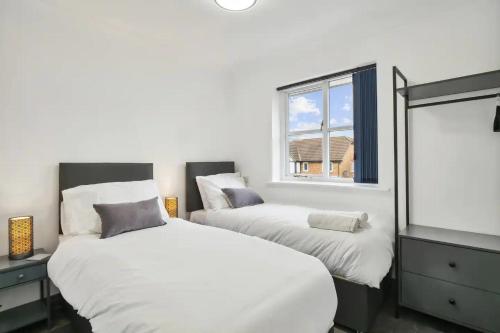 two beds in a room with a window at Long Stay Heaven Penthouse Near Longcross Studios in Brookwood