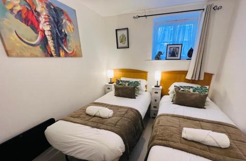 two twin beds in a room with a window at Safari Lodge - Close to Shopping Centre and Restaurants, Free Parking, Stylish and Amazing Artwork in Burton upon Trent