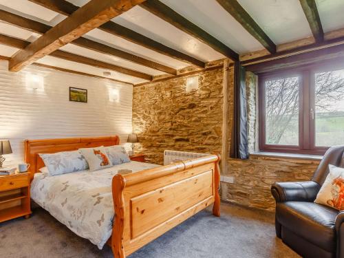 um quarto com uma cama de madeira e uma cadeira em 2 Bed in Polperro 90174 em Lansallos