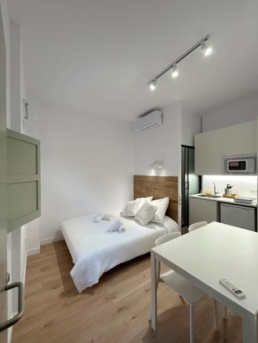 Dormitorio blanco con cama y mesa en SD Habitación céntrica con baño y minicocina, en Terrassa