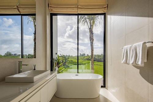 a bathroom with a tub and a large window at NEW Luxury 3BR, Jacuzzi Rooftop Rice Field, Staff in Legian