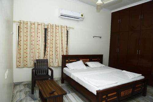 een slaapkamer met een bed en een stoel erin bij Sri Naari inn in Kondavīdu