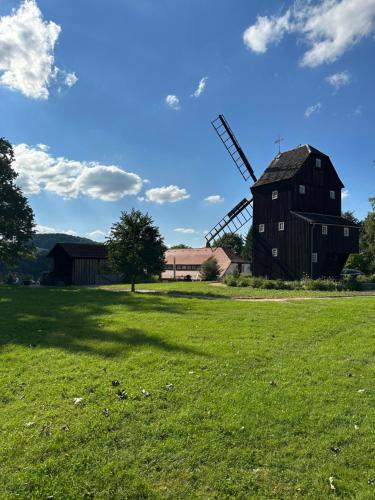 Eine Scheune und eine Windmühle auf einem Feld in der Unterkunft Ferienwohnung An der Berndtmühle in  Oderwitz