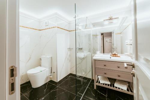 a white bathroom with a toilet and a sink at SunGarden Golf & Spa Resort in Cluj-Napoca