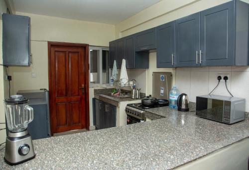 a kitchen with blue cabinets and a counter top at FG Homestay, Kampala Muyenga-Bukasa in Kampala